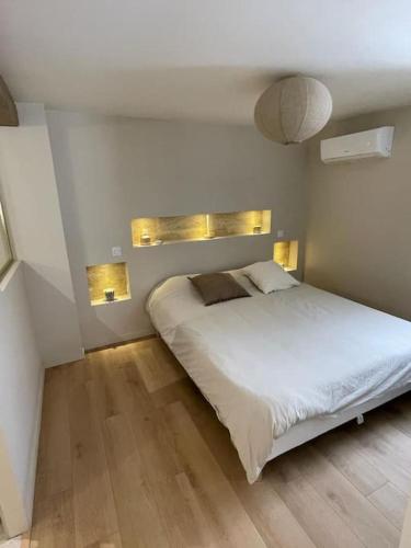 - une chambre avec un lit blanc et des lumières sur le mur dans l'établissement Maison en pierre avec sa piscine chauffée, à Le Bouscat