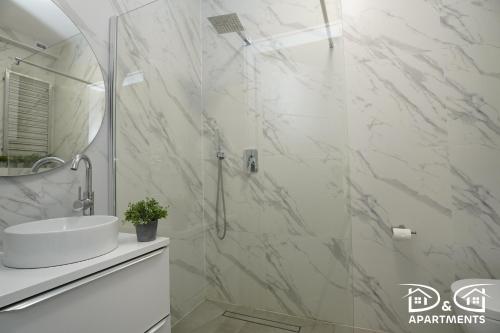 a white bathroom with a sink and a shower at Apartamenty Morze u Sary in Dziwnówek