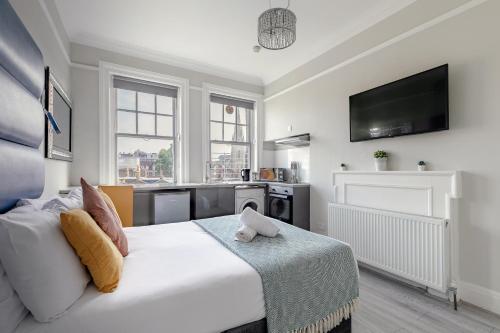 a bedroom with a white bed and a tv at Apartments in the Heart of High Street Kensington in London