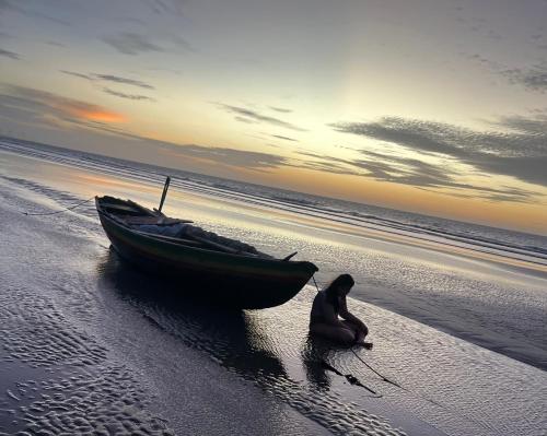 a woman sitting next to a boat on a beach at House Maceió 1 in Maceio