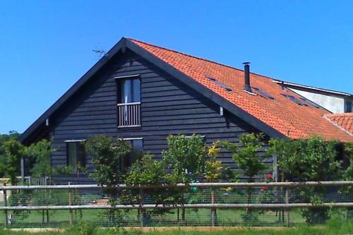 a black house with a red roof and a fence at Samphire Cottage in Stiffkey