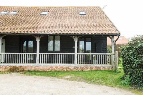 a house with a fence and a roof at Samphire Cottage in Stiffkey