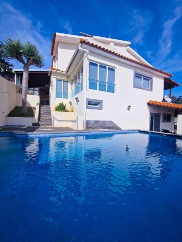 a villa with a blue swimming pool in front of a house at Basilio's Villa in Funchal