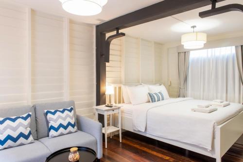 a bedroom with a large white bed and a couch at Resort Bangphlat in Bang O