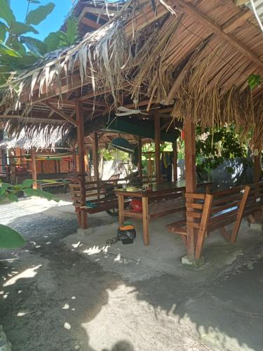 a hut with benches and a straw roof at Weeroona Huts Homestay Pacifico in San Isidro