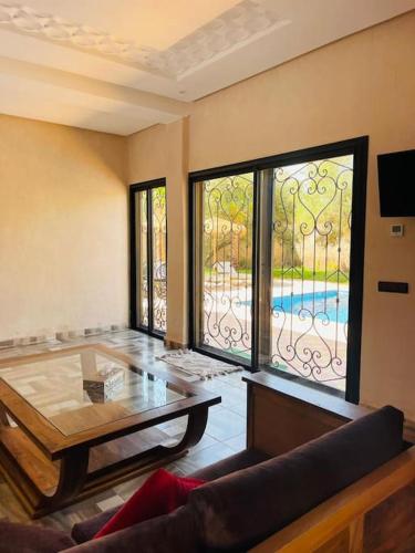 a living room with a table and a large window at Villa des tortues 3 Marrakech piscine privative sans vis à vis in Marrakech