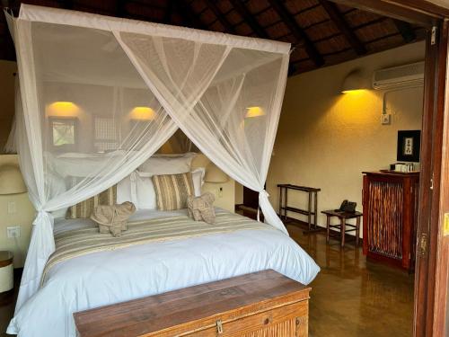 a bedroom with a white bed with a canopy at Nyati Safari Lodge in Hoedspruit