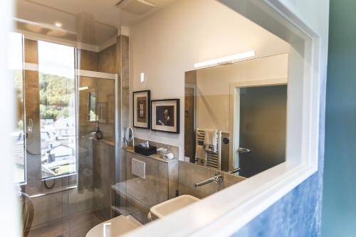 a bathroom with a sink and a shower and a mirror at Boutique Hotel LANDHAUSZEIT in Bad Münstereifel
