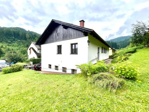 a white house with a black roof on a green field at Forestside Raceway Hideaway in Oberweg