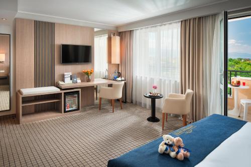 a hotel room with a teddy bear sitting on a bed at Landmark Creek Hotel Plovdiv in Plovdiv