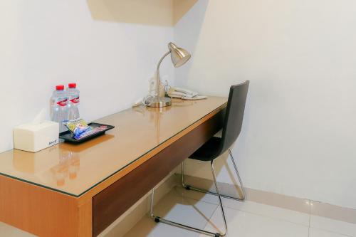 a desk with a lamp and a chair in a room at HOME Guesthouse in Surabaya