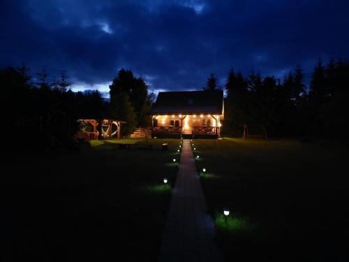 a house lit up at night with lights in front at Roztoczańska Ostoja in AdamÃ³w