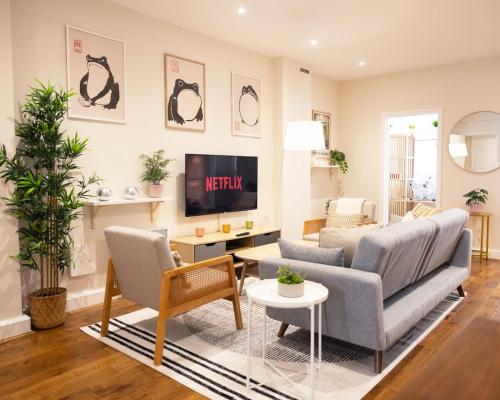 a living room with a couch and a tv at Two-Bed City Centre flat 100m from Trafalgar sqr in London