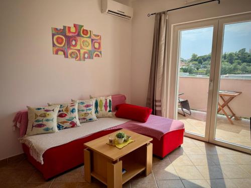 a living room with a red couch and a table at Apartments Maričić Rab Island in Rab