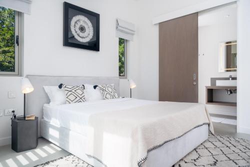a white bedroom with a large bed and a bathroom at Casa Alegria Beach Apartment in Pereybere