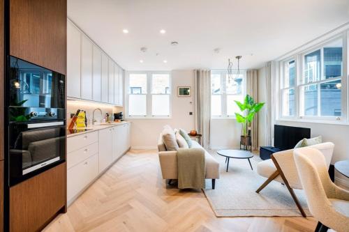 a kitchen with white cabinets and a living room at Two Bed Duplex in Covent Garden in London