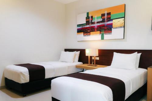 a hotel room with two beds and a painting on the wall at HOME Guesthouse in Surabaya