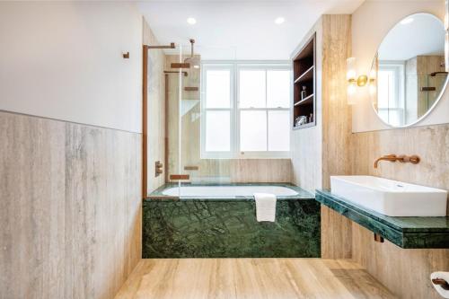 a bathroom with a tub and a sink and a mirror at Two Bed Duplex in Covent Garden in London