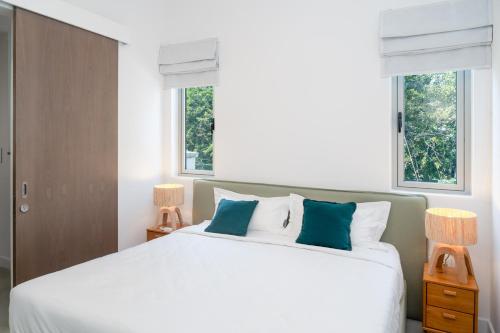a bedroom with a large white bed with two windows at Casa Alegria Beach Apartment in Pereybere