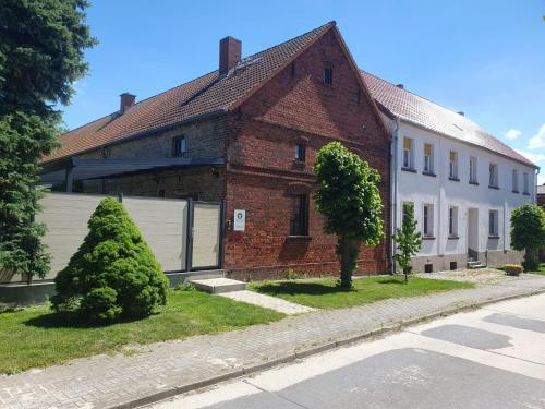 a red brick house with a white garage at Ferienwohnung Sieben Eulen in Garrey (Hoher Fläming) in Garrey