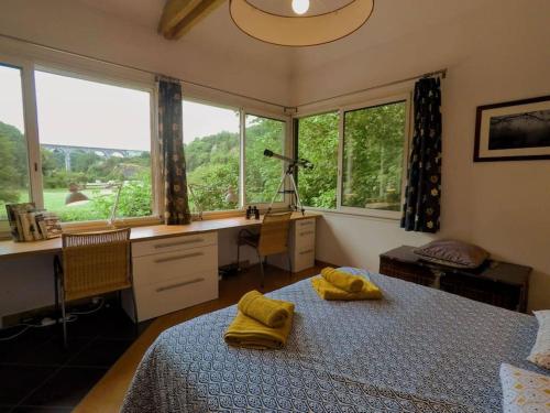 une chambre avec un lit, un bureau et des fenêtres dans l'établissement Lovely house by the Rance river, near Dinan port, à Lanvallay