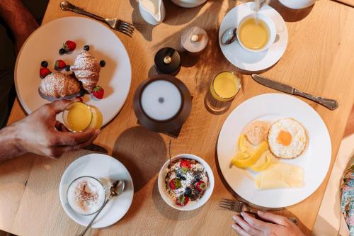 a table with plates of breakfast foods and drinks at Hotel Salzburg in Saalbach Hinterglemm