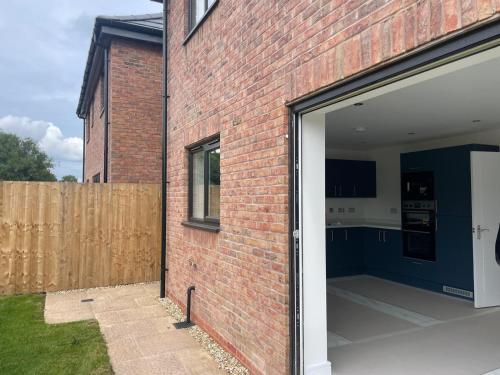 an open garage door of a brick building at Brand-New, 2 Private Bedrooms Available, Stunning Views, Stoke Hospital, Alton Towers, Keele University, Trentham Gardens, Free Parking & Wi-Fi in Silverdale