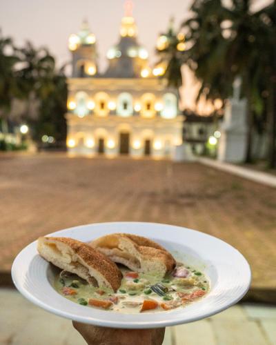 a person holding a plate of food with a sandwich at Fairfield by Marriott Goa Calangute in Calangute