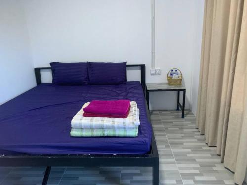 a bed with purple sheets and a pink towel on it at Maloop Cafe Bungalow in Koh Rong Island