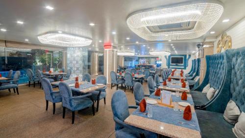 un restaurante con sillas y mesas azules en una habitación en The Nagpur Ashok, en Nagpur