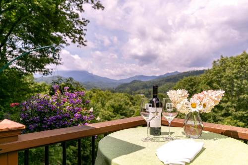 a table with two wine glasses and flowers on a balcony at Hinesight at Hound Ears in Valle Crucis