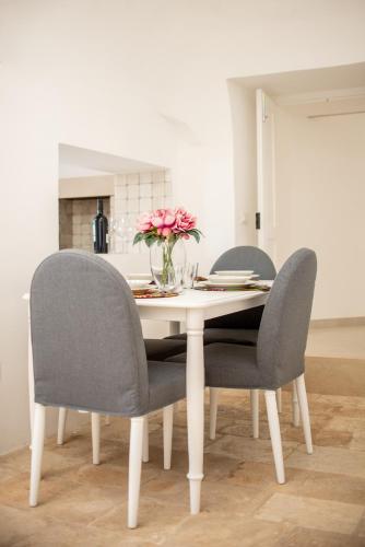 a dining room table with two chairs and a vase of flowers at I Trulli e la Luna in Alberobello