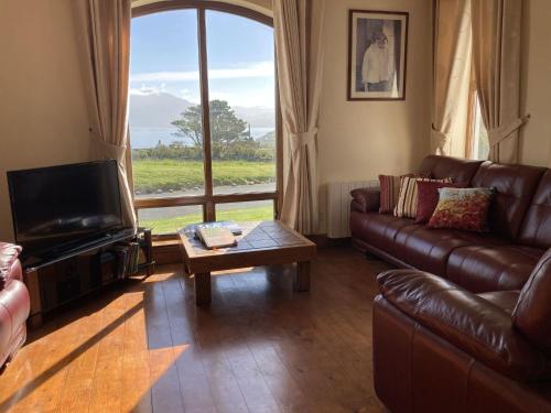 a living room with a leather couch and a large window at No 10 Coastguard Station in Renvyle