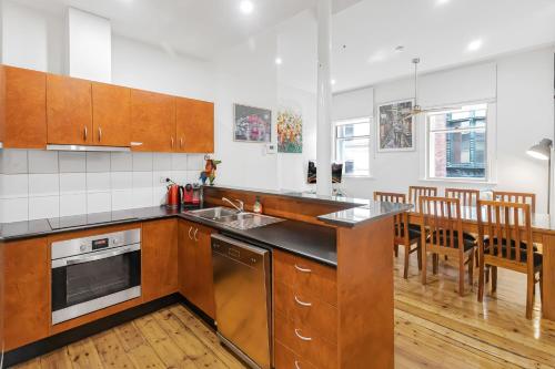 a kitchen with wooden cabinets and a table with chairs at Flinders Lane Apartments in Melbourne