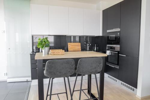 a kitchen with a wooden counter with two chairs at 18th Floor Helsinki High Point 1 BDR Apartment with City View - Free Garage Parking in Helsinki
