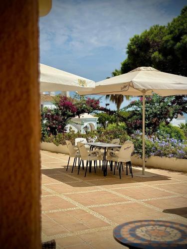 a table and chairs under an umbrella on a patio at Home 120, Mansion Alhamar in Sitio de Calahonda
