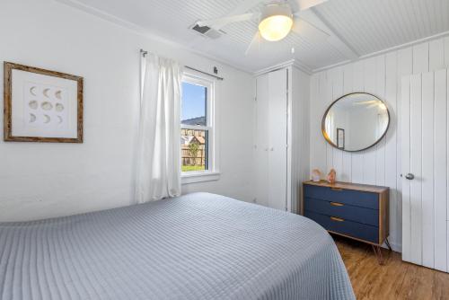a white bedroom with a bed and a mirror at KDH187 Lunar Tide in Kill Devil Hills