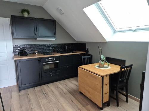 une cuisine avec des armoires noires et une table en bois dans l'établissement Logement neuf tout équipé, au Havre
