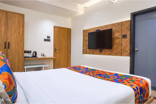 a bedroom with a bed and a tv on the wall at Oriva Shourya Residency - Nr Maharshi Karve Museum in Pune