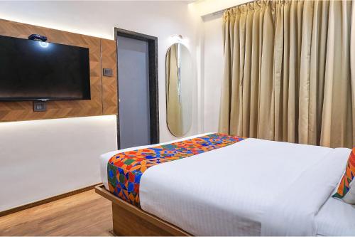 a bedroom with a bed and a flat screen tv at Oriva Shourya Residency - Nr Maharshi Karve Museum in Pune