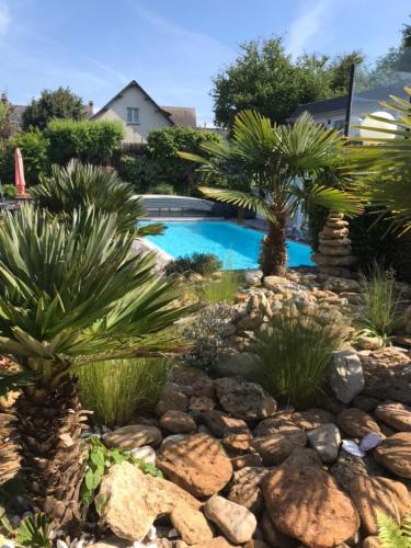 a garden with palm trees and a swimming pool at Hotel la piscine in Villers-sur-Mer