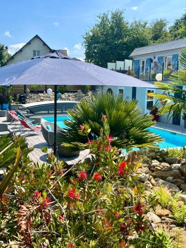 an umbrella next to a swimming pool with flowers at Hotel la piscine in Villers-sur-Mer