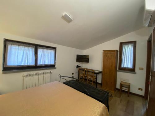 a bedroom with a bed and a desk and two windows at B&B Monteguzzo in Cigognola