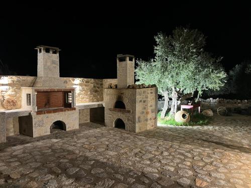 a stone house with an outdoor fireplace at night at Dome in Kharoúdha