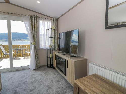 Una sala de estar con televisión y una gran ventana. en 11A Mansion View, en Helensburgh