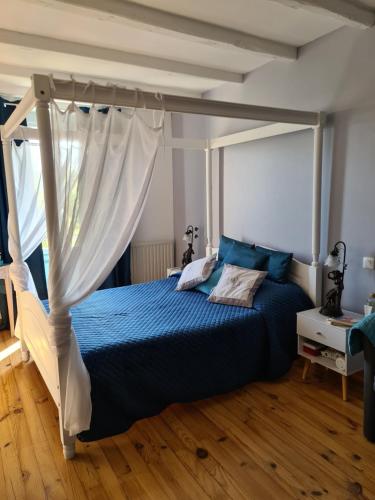 une chambre avec un lit à baldaquin dans l'établissement Maison de vacances en pierre avec piscine, à Saint-Mard