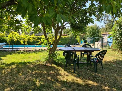 une table et des chaises sous un arbre dans un parc dans l'établissement Maison de vacances en pierre avec piscine, à Saint-Mard