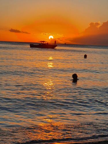 a boat in the ocean with a sunset in the background at TI OASIS Margarita Studio piscine et plage à P&Vac Village-Club in Bellevue