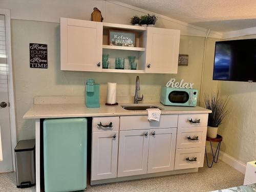 a kitchen with a counter and a sink and a refrigerator at Neptune's Grotto Old Florida Adventure Retreat in Spring Hill