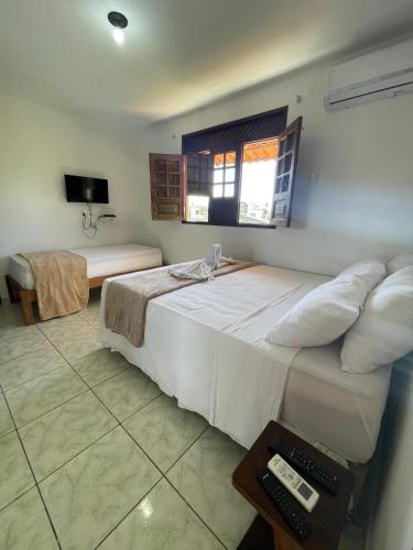 a bedroom with a large white bed and a television at Pousada Sunshine Patacho - Praia do Patacho - Rota Ecológica dos Milagres, Porto de Pedras in Pôrto de Pedras